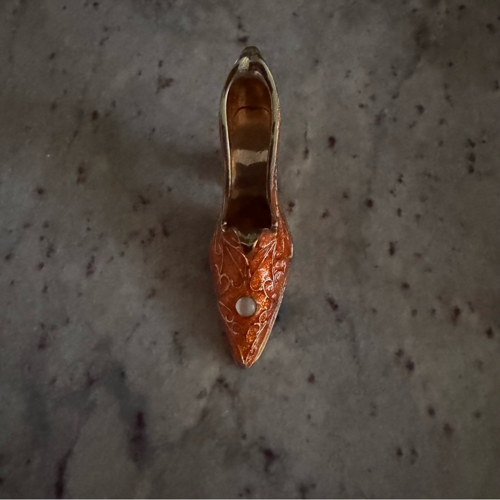 a gold and orange shoe with a cloudy crystal on top trinket